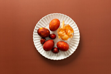 Colorful eggs are arranged on a plate alongside a small bowl of onion skins, how to dye eggs brown, creating a festive atmosphere for an Easter gathering at home