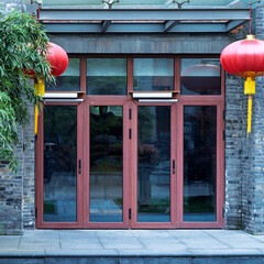 Close-up of a glass door on a traditional Chinese-style building adorned with red lanterns.