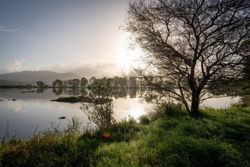 Autumn morning sun rising over a wetland habitat with reflection on the still water.