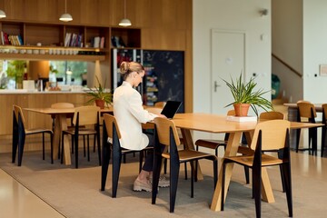 Professional Woman Working on Laptop in Modern Café Co-working Space With Plants