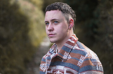 Young man with blue eyes looking into the distance on a forest trail during autumn © BRIN AKLE