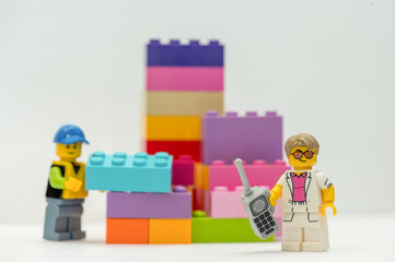 Naklejka premium A studio shot of Lego figure with mobile phone and building blocks. Lego is a very popular toy worldwide.