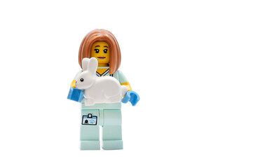 Naklejka premium A minifigures LEGO man: A veterinarian holding a small rabbit on a white background.