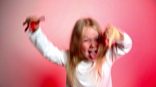 Excited child with red hair sticking out her tongue, holding sweets, thumbs down, against a red gradient background. Making food choice for healthy eating.
