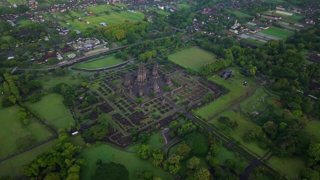 Aerial view of the ancient Prambanan Temple surrounded by lush green trees and grass plains, Yogyakarta, Jawa Tengah, Indonesia.