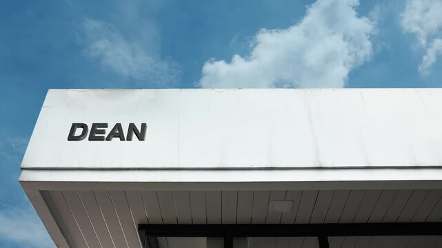 Dean word sign displayed on building facade against a clear blue sky, showcasing a modern educational institution or administrative office in daylight.