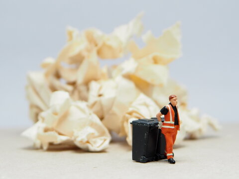 Mini toy of action figure at outdoor with blurred background. Miniature photography concept design. Minifigure of people character with garbage truck at urban city.