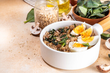 Tasty savory overnight oatmeal. Tasty non-sweet breakfast oats with spinach, mushrooms and eggs, on beige background ingredients for cooking