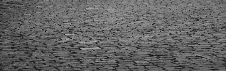 Old grey gray cobblestone sidewalk, pavement, perspective view cobbles pebble coddled stones in an...