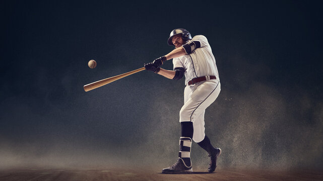 Baseball batter making contact with ball through dust cloud showing explosive athletic power. Concept of strength, motion accuracy, competitive spirit for sports coaching and visual education.