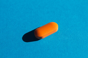 Orange pill on bright blue background with shadow