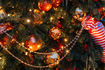 Golden red Christmas balls and beads hanging on the Christmas tree, festive details and winter decorations