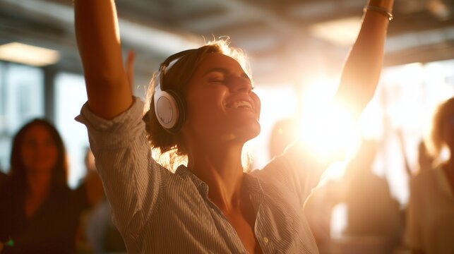 A woman raises her arms in excitement while listening to music through headphones in a vibrant setting. The woman enjoys the joyful atmosphere created by the lively crowd around he