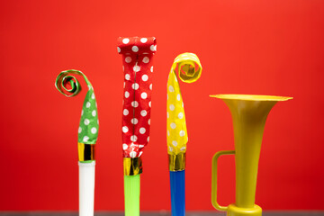 Colorful party blowers on a red background. Concept of a party or a holiday celebration
