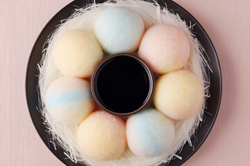Colorful mochi ice cream balls arranged in circular pattern with dark sauce in center