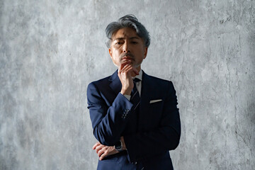 グレー背景の前でスーツ姿の男性