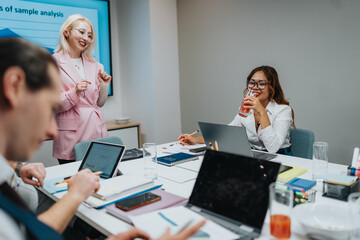 A diverse team gathers around a conference table as a woman in a pink blazer leads a presentation...