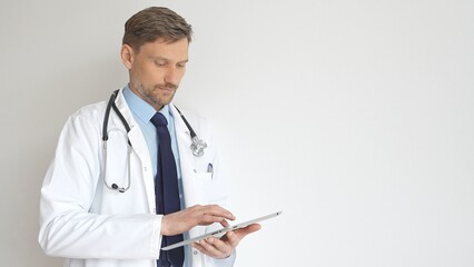 Confident doctor man wearing stethoscope and white coat, standing with crossed arms and gazing...