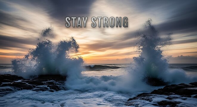 Dramatic ocean waves crash against dark rocks under a vibrant sunset sky, with the inspiring message stay strong superimposed on the scene