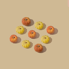 Autumn pattern with colorful pumpkins on a beige backround.Minimal thanksgiving celebrating concept.Flat lay
