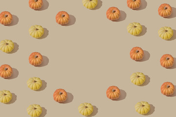 Autumn pattern with colorful pumpkins on a beige backround.Minimal thanksgiving celebrating concept.Flat lay.Copy space