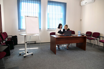 Women during a business presentation point to charts on the flipchart while discussing strategy.