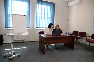 Women during a business presentation point to charts on the flipchart while discussing strategy.