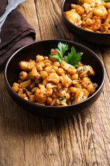 Cauliflower and chickpeas curry salad on wooden table, healthy vegan food
