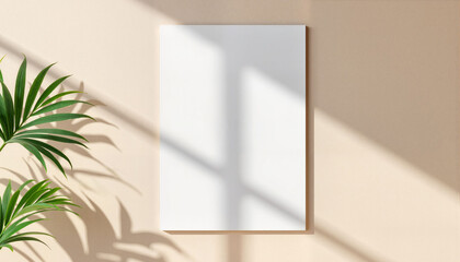 Blank poster frame on wall with natural sunlight and plant  