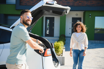 Couple charging electric car at home using renewable energy