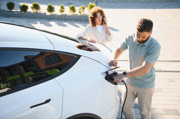 Couple charging electric car at home, embracing green energy and sustainable lifestyle