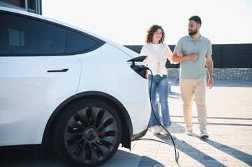 Couple walking away while charging electric car at home
