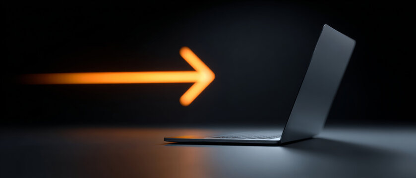 A laptop is open and facing away from the camera with a glowing orange arrow pointing towards it on a dark background