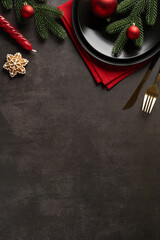 Festive vertical Christmas and New Year table scene featuring pine branches, red ornaments, a star cookie, and elegant flatware on a dark background. Ideal for holiday greetings and promotions © ActionGP