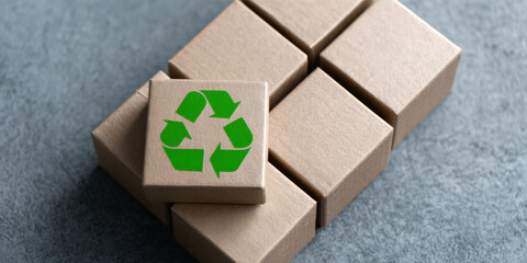 A green recycling symbol is on a cardboard box among other boxes
