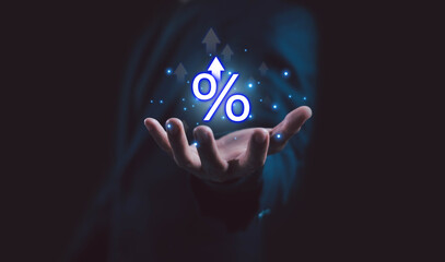 Businessman hand holding glowing percentage sign with upward arrows symbolizes interest rate growth, investment profit, and financial success concept in modern digital economy.