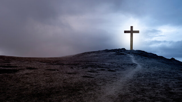 Path toward Christian cross on the hill with dark dramatic sky background. Concept of Christianity, religious, faith, Jesus, or belief