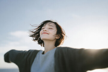 Joyful portraits of a young woman with open arms under the blue sky in natural sunlight