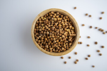 coriander seeds in a wooden bowl on a white background