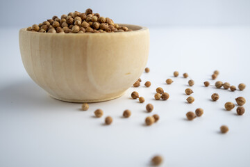 coriander seeds in a wooden bowl on a white background