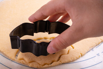 pressing dough into a bat-shaped cookie