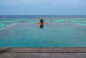 Tranquil closeup calm sea water waves with palm trees. Man tourist posing, Tropical island beach landscape exotic shore coast. Summer vacation, holiday amazing nature. Relax paradise, Maldives.