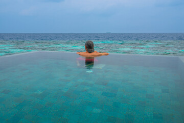 Tranquil closeup calm sea water waves with palm trees. Man tourist posing, Tropical island beach landscape exotic shore coast. Summer vacation, holiday amazing nature. Relax paradise, Maldives.