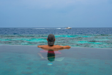 Tranquil closeup calm sea water waves with palm trees. Man tourist posing, Tropical island beach landscape exotic shore coast. Summer vacation, holiday amazing nature. Relax paradise, Maldives.