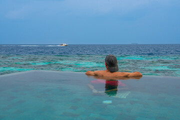 Tranquil closeup calm sea water waves with palm trees. Man tourist posing, Tropical island beach landscape exotic shore coast. Summer vacation, holiday amazing nature. Relax paradise, Maldives.