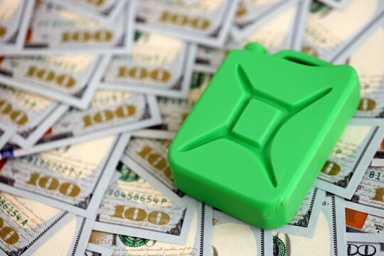 Petroleum or gasoline canister reservoir lies on big amount of dollar bills. Concept of petrol prices in United States - Powered by Adobe