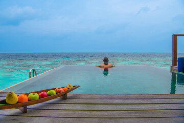 Tranquil closeup calm sea water waves with palm trees. Man tourist posing, Tropical island beach landscape exotic shore coast. Summer vacation, holiday amazing nature. Relax paradise, Maldives.