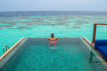 Tranquil closeup calm sea water waves with palm trees. Man tourist posing, Tropical island beach landscape exotic shore coast. Summer vacation, holiday amazing nature. Relax paradise, Maldives.