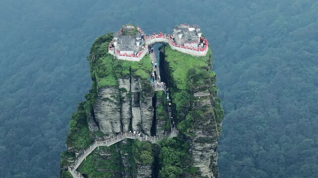 Aerial view of the Fanjingshan temples perched atop the dramatic rock formations, connected by bridges, amidst the lush greenery, Fanjingshan, Guizhou, China.