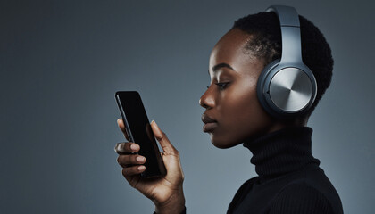 Woman wearing over-ear headphones holding smartphone against dark gradient background